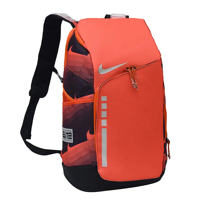 Nike athletic backpack in bright orange and black, featuring a reflective silver Nike Swoosh on the front, a zippered pocket, and a patterned soccer ball partially tucked inside.