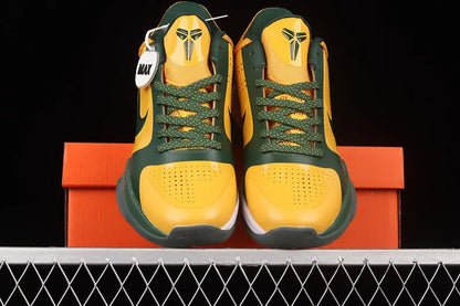 A pair of yellow and green Nike basketball sneakers displayed on top of an orange shoebox against a black background.