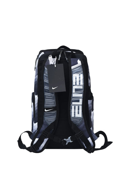 Nike athletic backpack shown from the back, featuring a black, gray, and white patterned design with large vertical white text and a black hangtag with a white Nike swoosh.