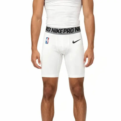White Nike Pro basketball shorts worn by a model, featuring a gray elastic waistband with black lettering and a black Nike swoosh on the left hip.
