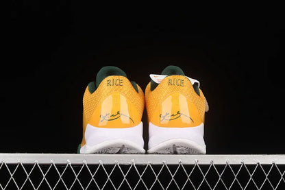 A pair of yellow and green sneakers shown from the back, resting on a white metal grid against a solid black background. The word 'RICE' is printed on the heel area.