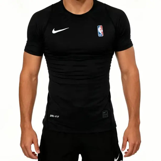 A man wearing a black Nike Dri-FIT athletic compression shirt with a white swoosh on the chest and an NBA logo on the opposite chest, shown against a plain white background.