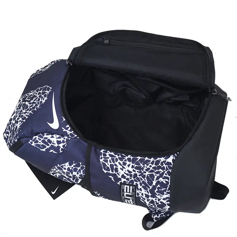 A Nike duffel bag in navy blue and white with a cracked pattern, shown open to display its black interior. The bag features a white Nike swoosh on the side and a black-and-white striped logo patch on the front.