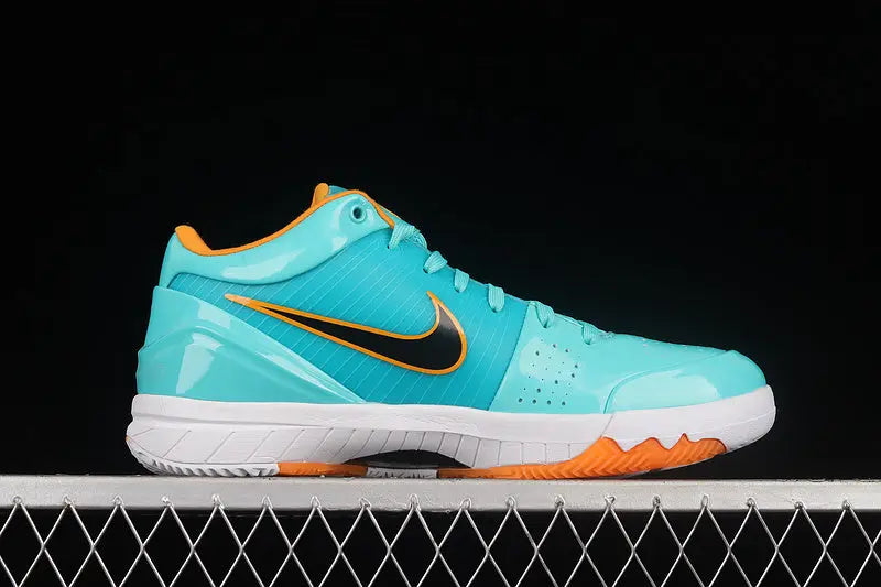 A Nike basketball shoe in a vibrant turquoise blue with a black Swoosh, orange accents on the collar and outsole, and a white midsole, shown in profile against a black background.
