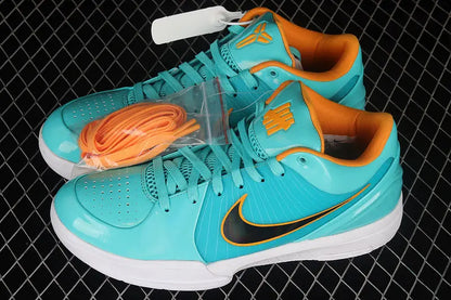 A pair of Nike low-top sneakers in a vibrant turquoise and orange colorway, displayed on a black wire mesh background. The shoes feature a glossy turquoise upper, bright orange lining and laces, a black Nike Swoosh, and white soles.