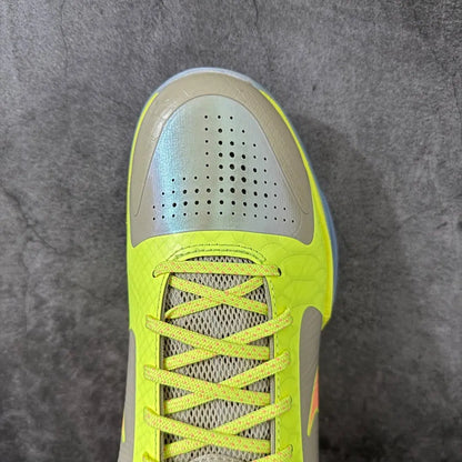 A close-up top-down view of a Nike sneaker, showing the toe box, laces, and textured mesh upper in neon yellow and light gray on a gray textured background.