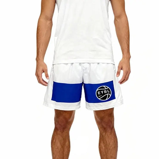 A model wearing white athletic shorts with a bold royal blue side panel and a circular black-and-white logo on the left leg, paired with a white tank top against a plain white background.