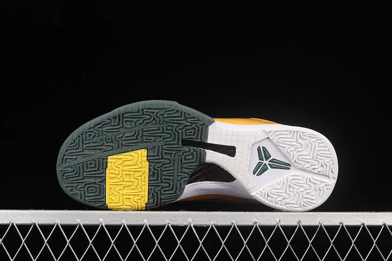 The outsole of a basketball shoe is shown against a black background, featuring a dark gray and white tread pattern with a bright yellow accent block and a white midsole.