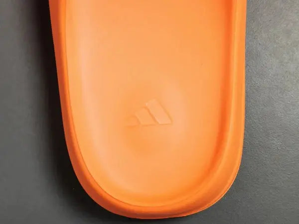 "adidas Yeezy Slide x Enflame Orange – vibrant orange slide with soft EVA foam, minimalist design, and ridged outsole for comfort and traction."