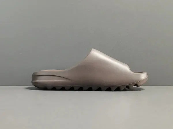 "adidas Yeezy Slide x Soot – dark earth-tone slide with soft EVA foam, minimalist design, and ridged outsole for comfort and traction."