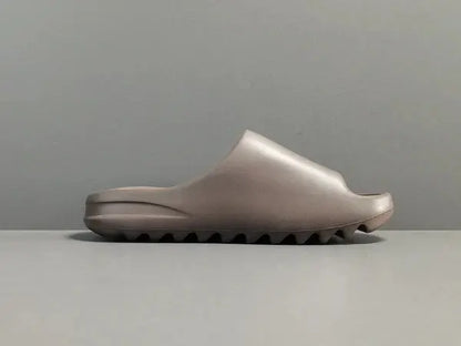 "adidas Yeezy Slide x Soot – dark earth-tone slide with soft EVA foam, minimalist design, and ridged outsole for comfort and traction."