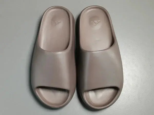 "adidas Yeezy Slide x Soot – dark earth-tone slide with soft EVA foam, minimalist design, and ridged outsole for comfort and traction."
