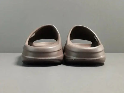 "adidas Yeezy Slide x Soot – dark earth-tone slide with soft EVA foam, minimalist design, and ridged outsole for comfort and traction."