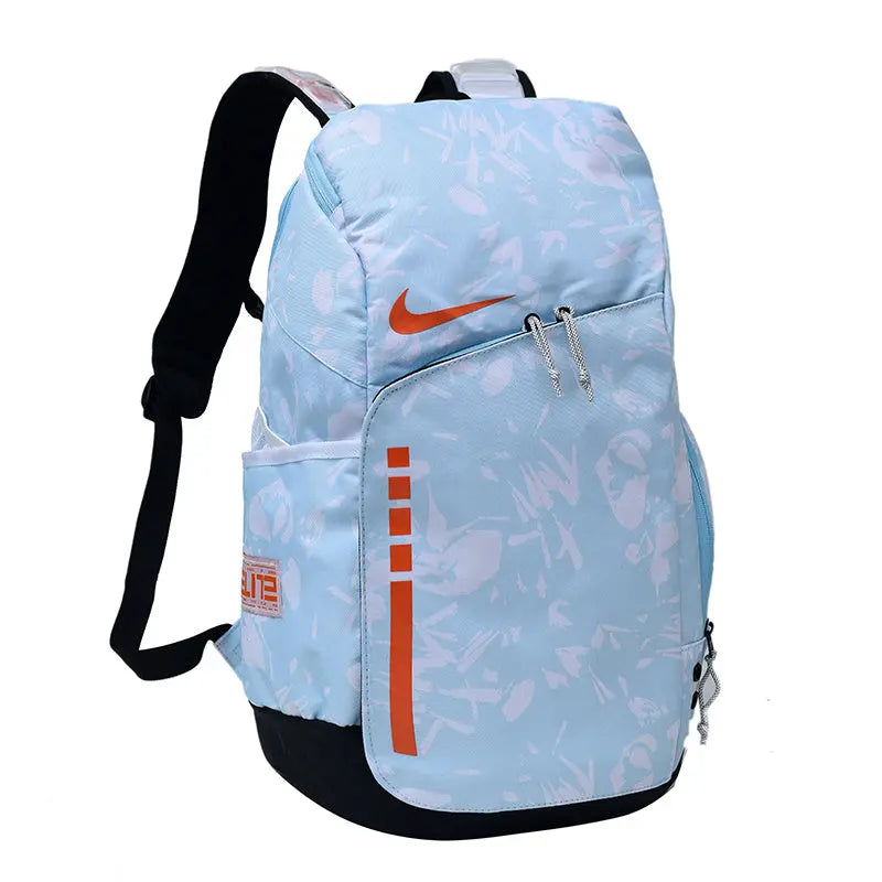 A light blue Nike backpack with a subtle white graffiti-style pattern, orange swoosh logo, and orange vertical stripe detail, shown on a plain white background.