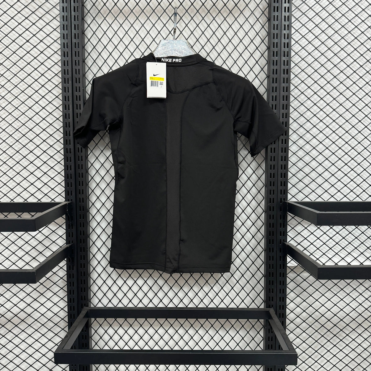 A black short-sleeve button-front overshirt or jacket from the brand NEE PJS, hanging on a white hanger against a black metal mesh display rack.